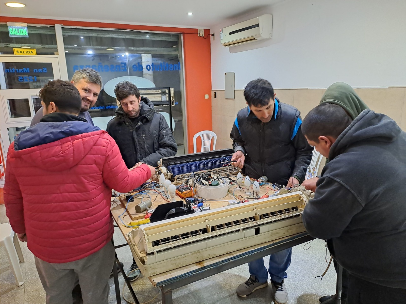 Alumnos practicando sobre un equipo de aire acondicionado en el taller